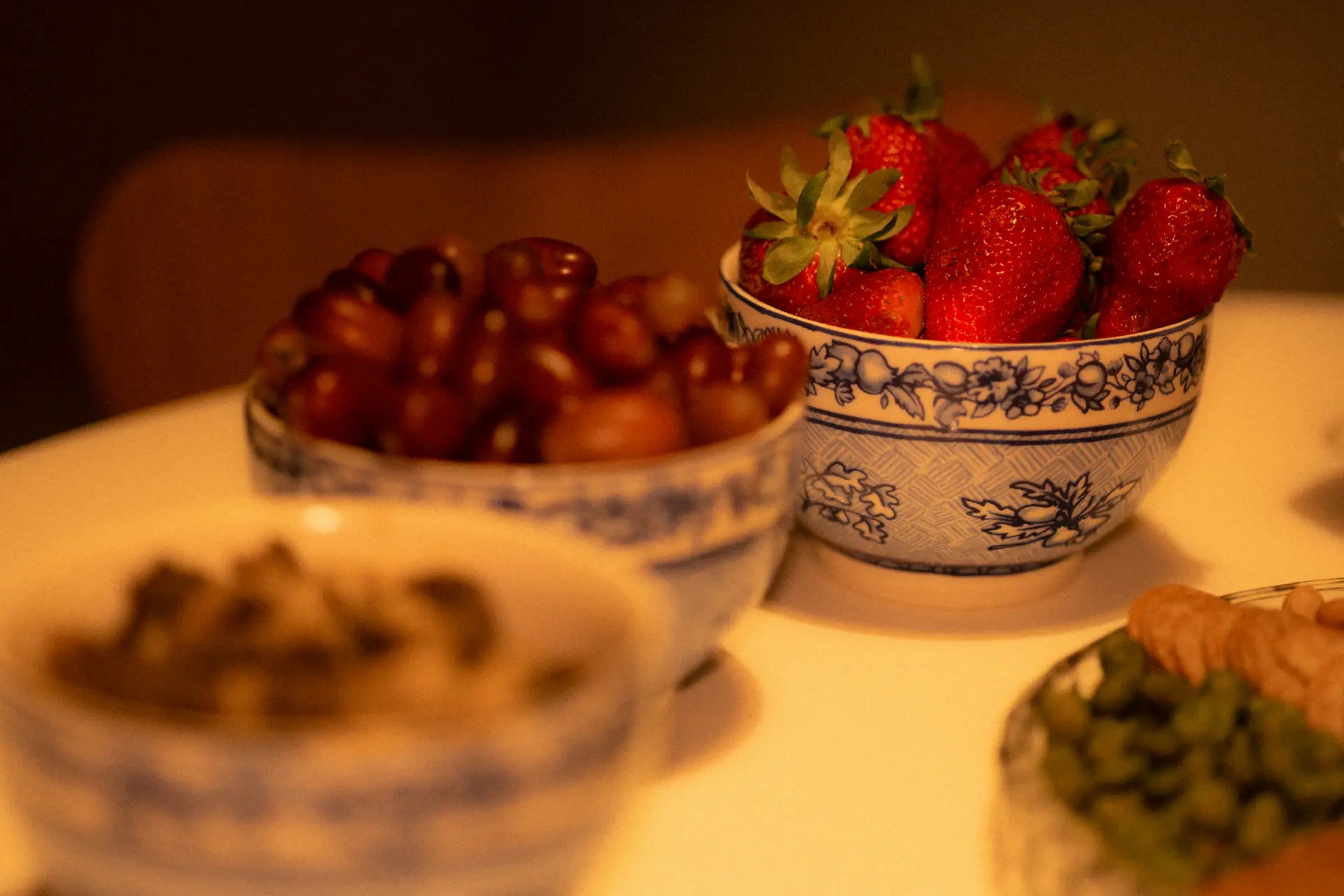Bowls of strawberries, grapes and nuts on a table in warm light