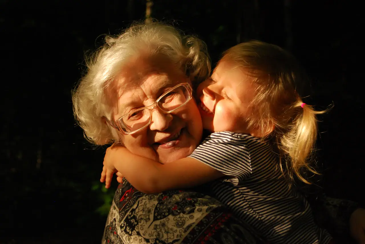 A grandmother being hugged by her granddaughter in warm light