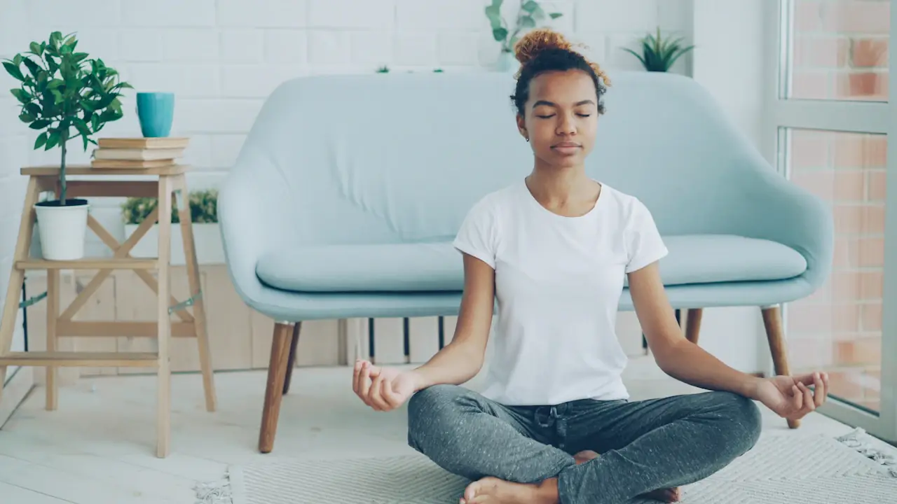 A young woman meditating cross-legged at home