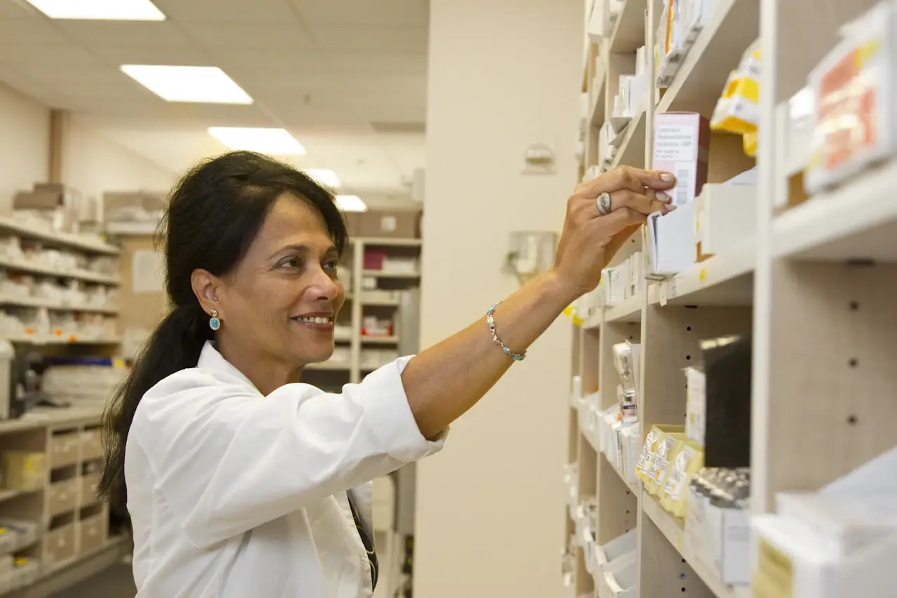 A pharmacist reaching for medicine on a pharmacy shelf