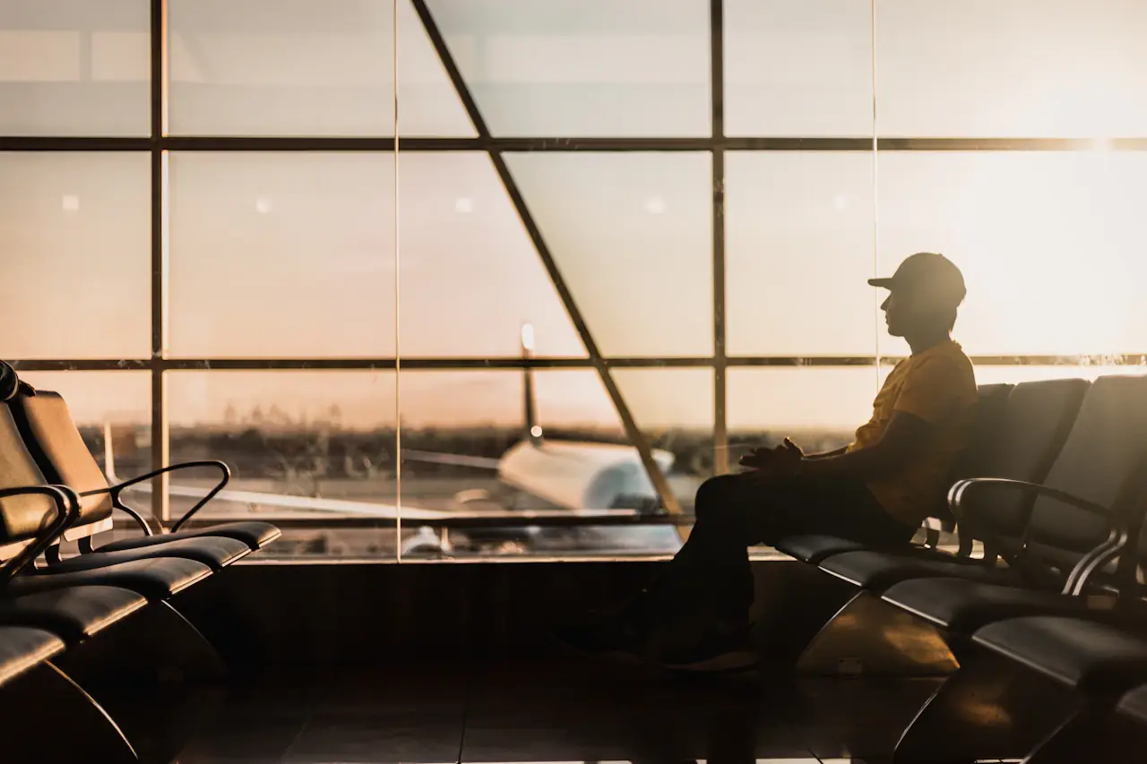 A traveller waiting at an airport window at sunset